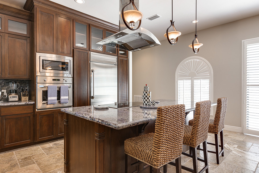 Example of a mid-sized transitional travertine floor eat-in kitchen design in Austin with an undermount sink, granite countertops, stainless steel appliances and an island