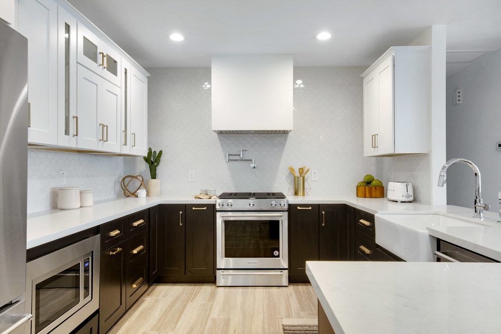 Mid-sized contemporary u-shaped separate kitchen in Phoenix with a farmhouse sink, shaker cabinets, white cabinets, marble benchtops, white splashback, ceramic splashback, stainless steel appliances, light hardwood floors, no island, brown floor and white benchtop.