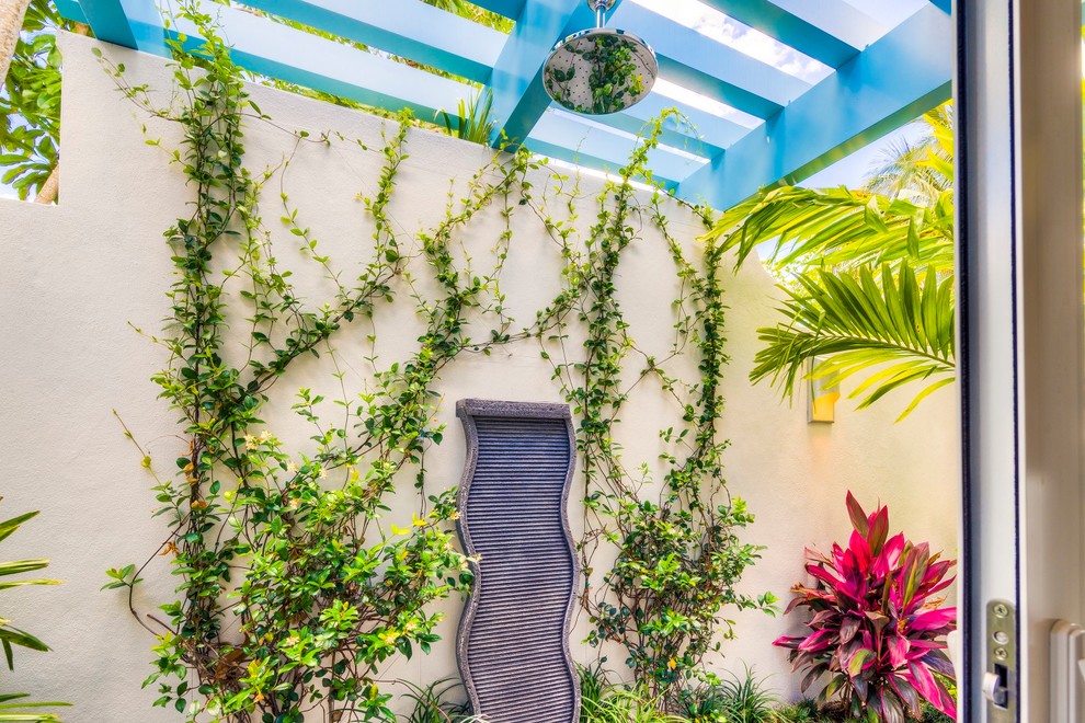 Tropical patio in Miami with an outdoor shower and a pergola.