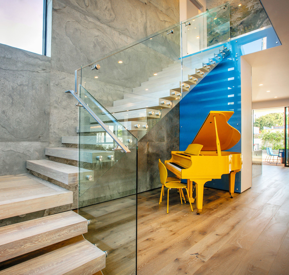 Contemporary wood l-shaped staircase in Los Angeles with open risers and glass railing.