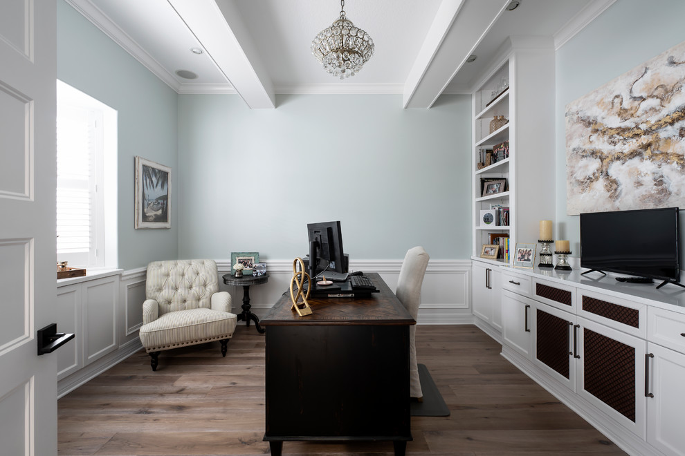 This is an example of a large traditional home office in Tampa with blue walls, medium hardwood floors, no fireplace, a freestanding desk and brown floor.