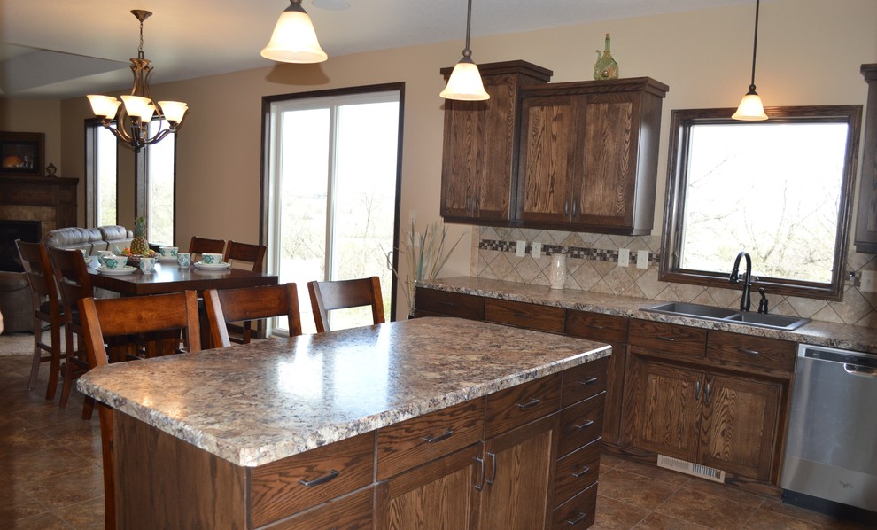 Example of a mid-sized mountain style l-shaped laminate floor and beige floor eat-in kitchen design with a drop-in sink, recessed-panel cabinets, dark wood cabinets, granite countertops, beige backsplash, stainless steel appliances, an island and ceramic backsplash