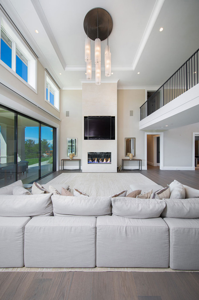 Photo of a large contemporary open concept living room in San Francisco with white walls, medium hardwood floors, a wood stove, a plaster fireplace surround, a wall-mounted tv, brown floor and coffered.