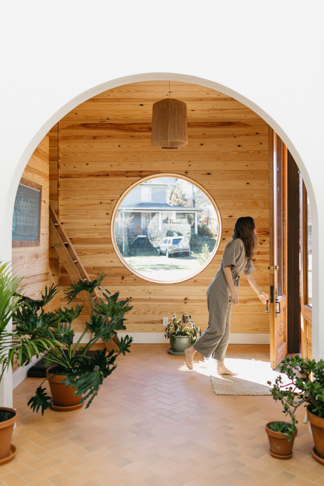Inspiration for a contemporary terra-cotta tile, vaulted ceiling and shiplap wall entryway remodel in Other with white walls and a medium wood front door