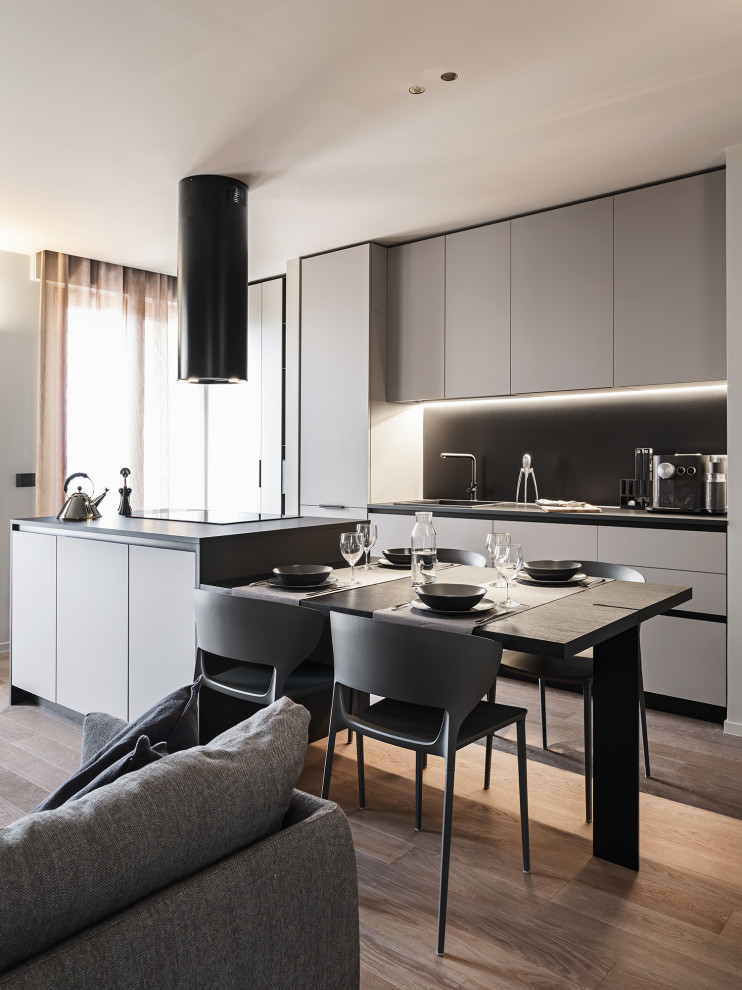 Photo of a small modern galley open plan kitchen in Bari with flat-panel cabinets, black cabinets, laminate benchtops, black appliances, with island, grey floor, black benchtop and recessed.