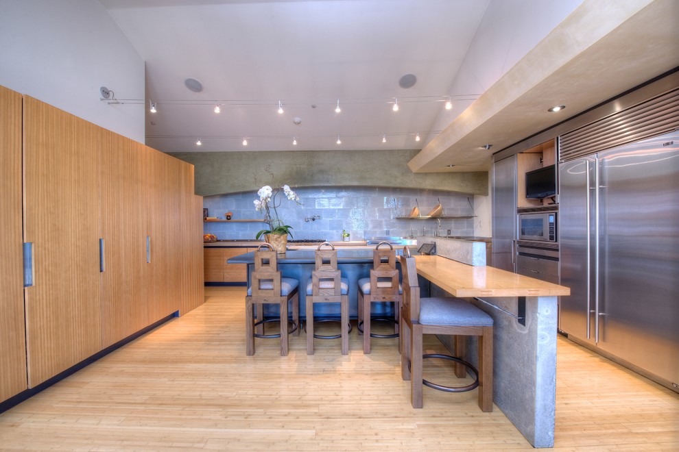 Inspiration for a contemporary l-shaped kitchen in San Francisco with flat-panel cabinets, light wood cabinets, wood benchtops, grey splashback, stainless steel appliances, light hardwood floors and multiple islands.