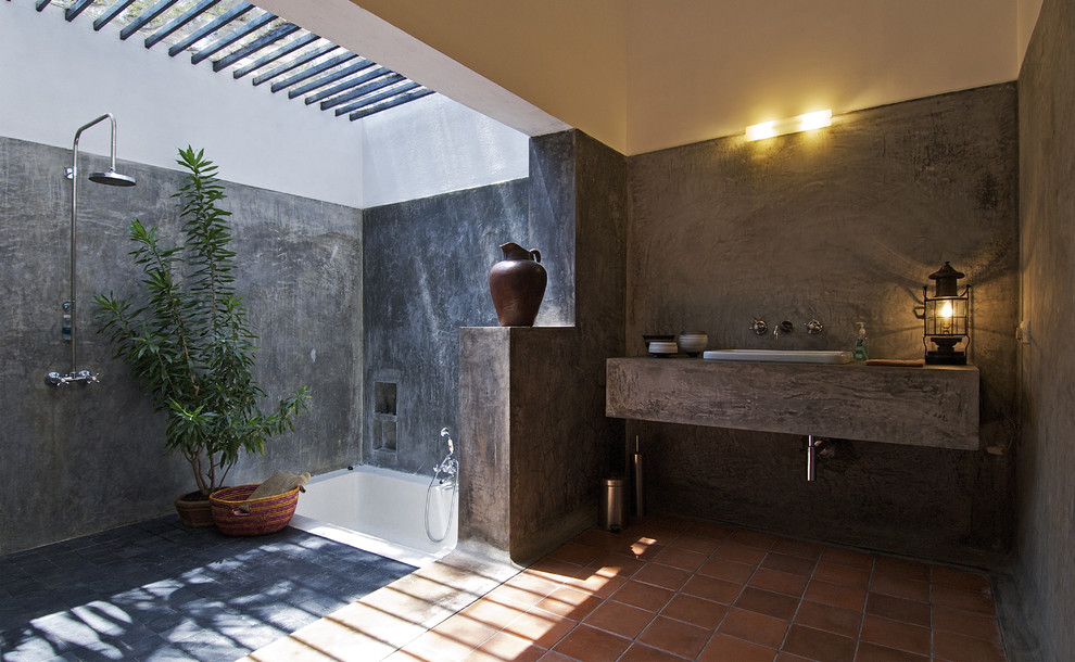 Inspiration for an industrial master bathroom in Mumbai with a drop-in tub, an open shower, multi-coloured walls, terra-cotta floors, a drop-in sink, concrete benchtops, orange floor and an open shower.