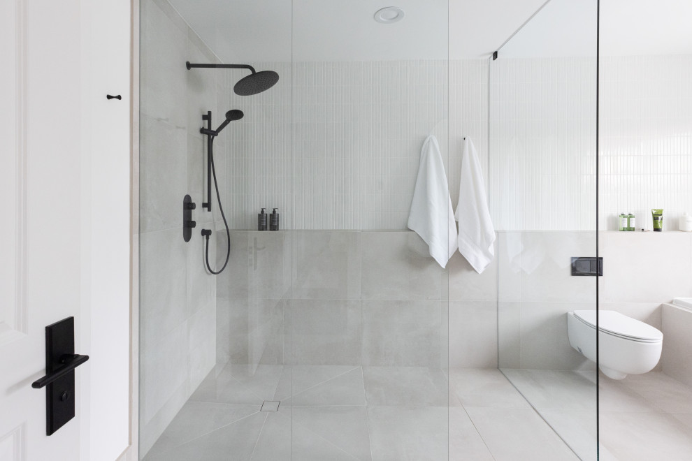 This is an example of a large modern ensuite bathroom in Toronto with a built-in shower, a wall mounted toilet, white tiles, porcelain tiles, white walls, porcelain flooring, grey floors, an open shower and a wall niche.