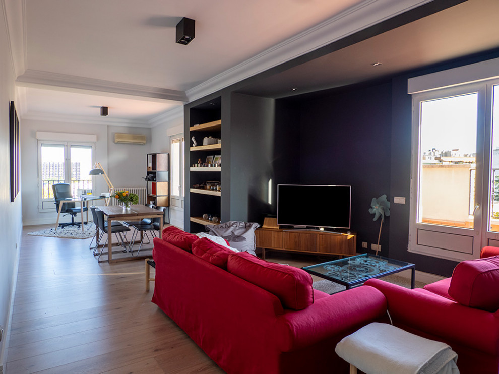 Mid-sized industrial open concept living room in Madrid with grey walls, medium hardwood floors, a freestanding tv and beige floor.