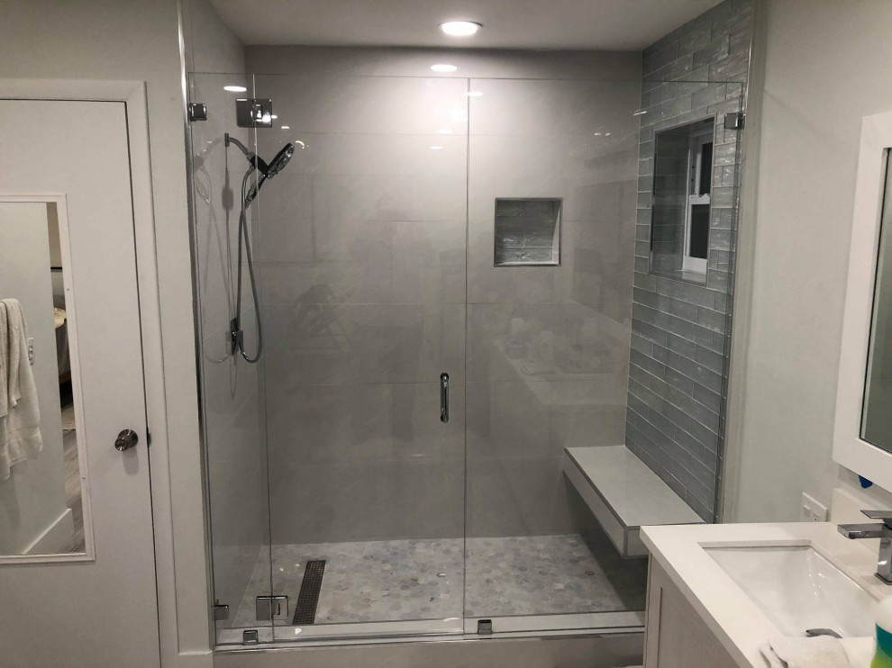 This is an example of a large beach style master bathroom in Other with furniture-like cabinets, white cabinets, an open shower, a one-piece toilet, black and white tile, ceramic tile, white walls, ceramic floors, a drop-in sink, granite benchtops, grey floor, a hinged shower door, white benchtops, a shower seat, a single vanity, a freestanding vanity, vaulted and wood walls.