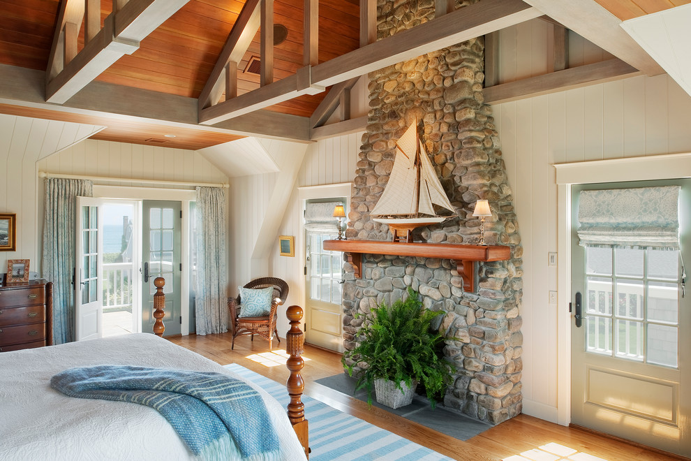 Inspiration for a large beach style master bedroom in Providence with white walls, medium hardwood floors, a standard fireplace and a stone fireplace surround.