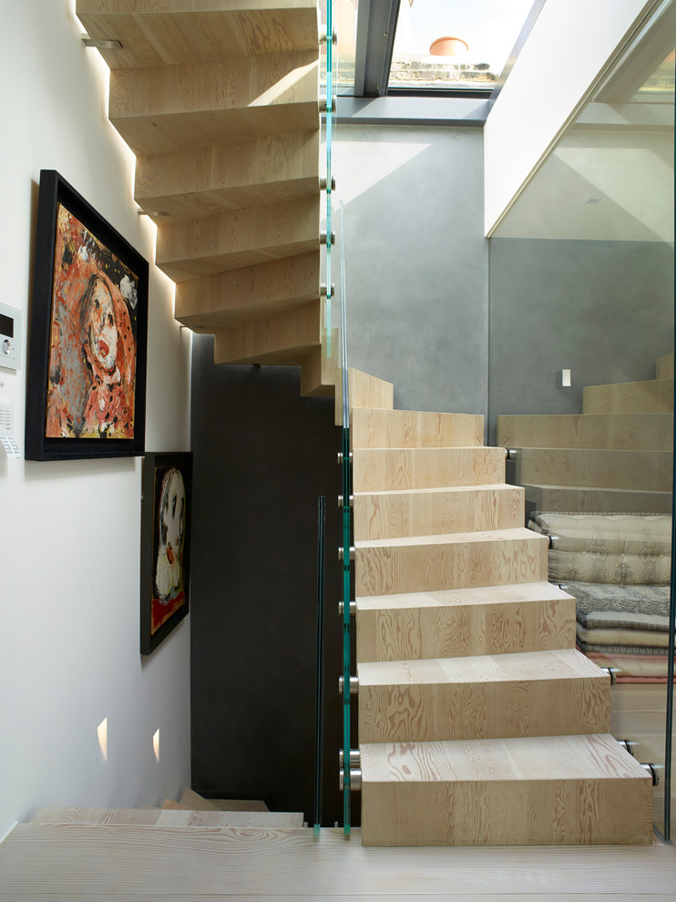 Photo of a mid-sized contemporary wood spiral staircase in London with wood risers and glass railing.