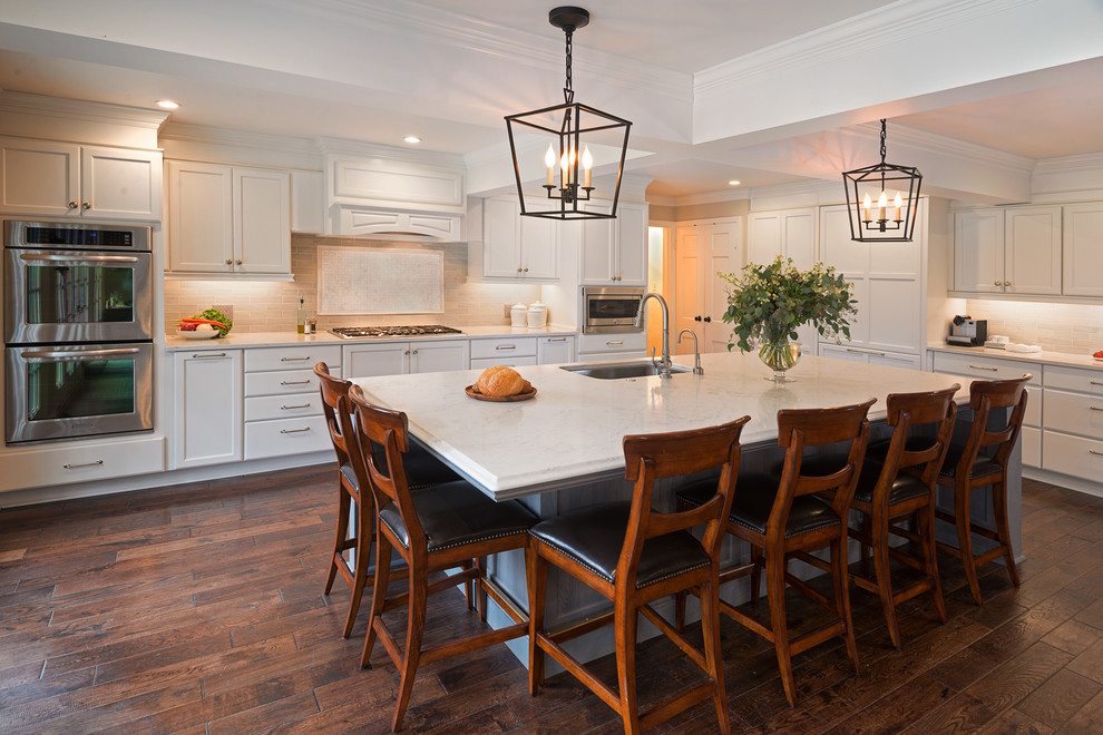 Huge transitional l-shaped medium tone wood floor open concept kitchen photo with flat-panel cabinets, white cabinets, marble countertops, gray backsplash, porcelain backsplash, paneled appliances and an island