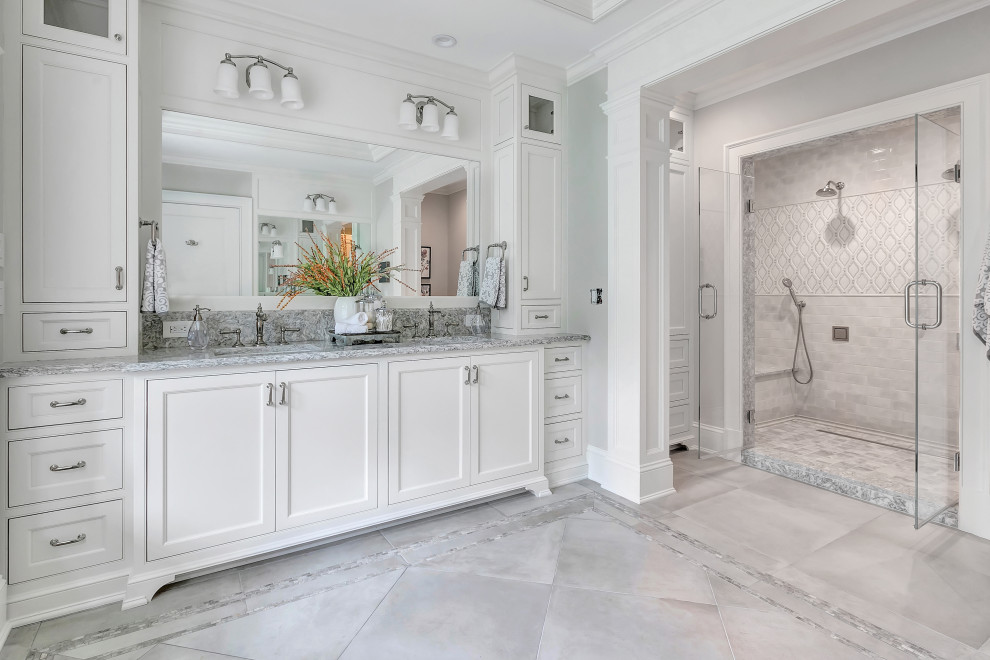 This is an example of a large transitional master bathroom in New York with beaded inset cabinets, white cabinets, an alcove shower, ceramic tile, grey walls, porcelain floors, an undermount sink, engineered quartz benchtops, a hinged shower door, gray tile, grey floor, grey benchtops, a double vanity, a built-in vanity and recessed.