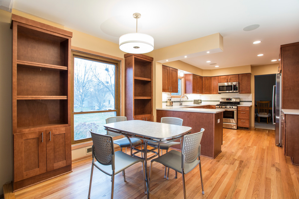 Photo of a mid-sized traditional u-shaped eat-in kitchen in Minneapolis with an undermount sink, shaker cabinets, medium wood cabinets, quartzite benchtops, white splashback, subway tile splashback, stainless steel appliances, light hardwood floors and a peninsula.