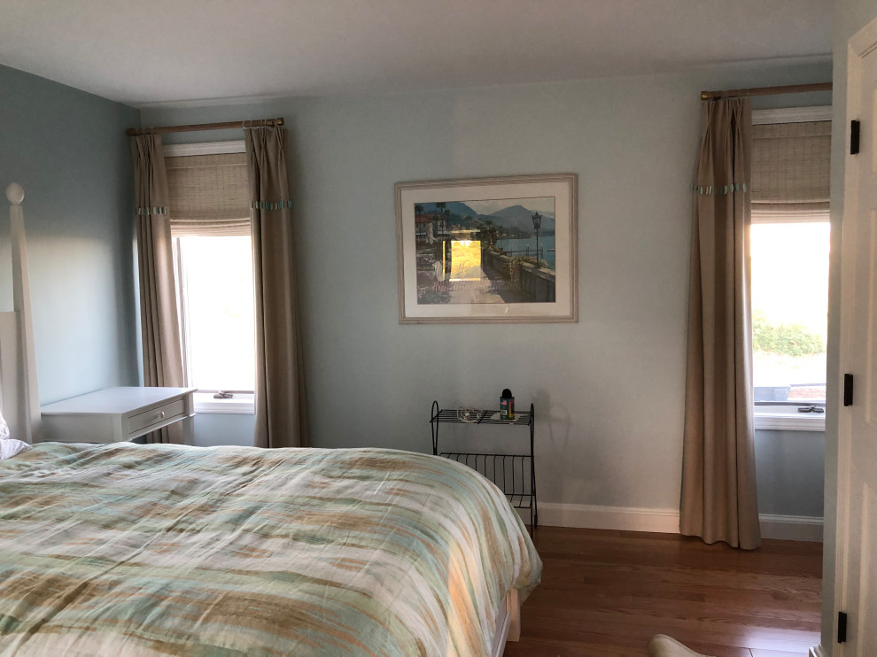 This is an example of a beach style master bedroom in Boston with blue walls, dark hardwood floors and brown floor.