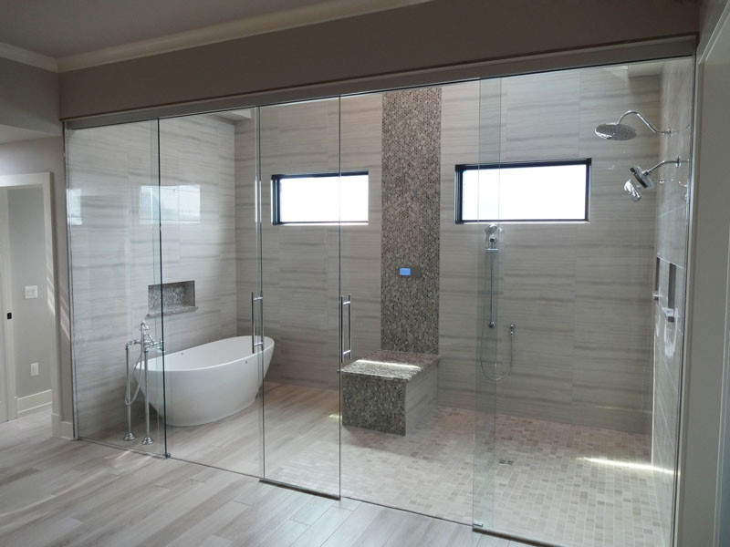 Photo of a large contemporary master bathroom in Chicago with a freestanding tub, a double shower, gray tile, porcelain tile, grey walls, light hardwood floors, grey floor and a sliding shower screen.