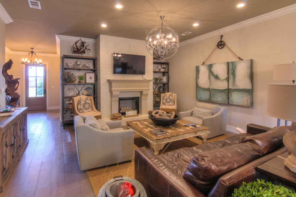 Mittelgroßes Wohnzimmer mit beiger Wandfarbe, hellem Holzboden, Kamin, Kaminumrandung aus Backstein und grauem Boden in Nashville