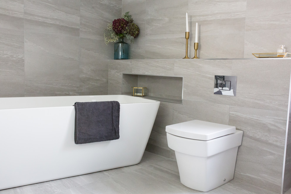 Inspiration for a large contemporary kids bathroom in Other with flat-panel cabinets, grey cabinets, a freestanding tub, an open shower, a one-piece toilet, gray tile, ceramic tile, grey walls, ceramic floors, a wall-mount sink, grey floor and an open shower.