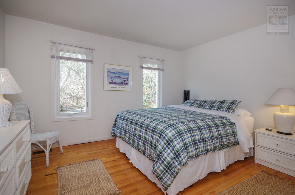 Photo of a mid-sized contemporary guest bedroom in New York with white walls, medium hardwood floors, no fireplace and brown floor.