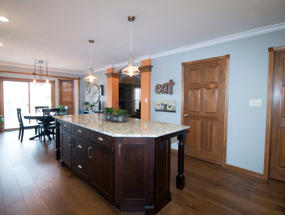 Example of a large transitional l-shaped medium tone wood floor eat-in kitchen design with an undermount sink, shaker cabinets, white cabinets, granite countertops, gray backsplash, stone tile backsplash, stainless steel appliances and an island