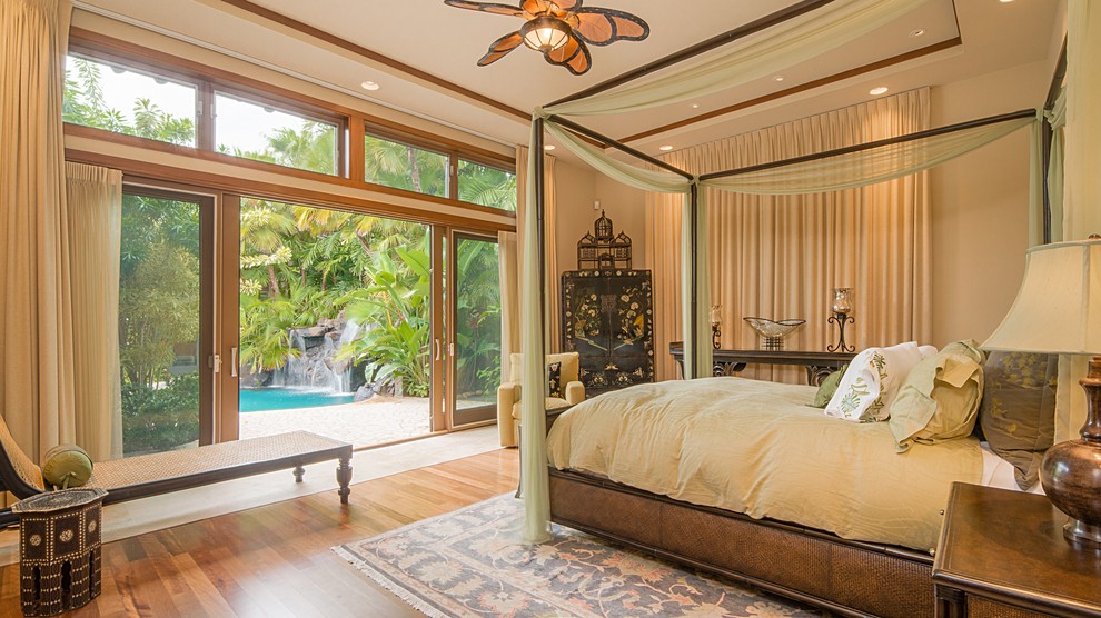 Photo of a tropical bedroom in Hawaii with beige walls and medium hardwood floors.