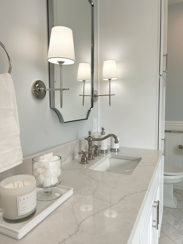 Example of a mid-sized transitional master gray tile and marble tile marble floor, gray floor, double-sink and wainscoting freestanding bathtub design with shaker cabinets, white cabinets, a two-piece toilet, blue walls, an undermount sink, quartz countertops, a hinged shower door, gray countertops and a built-in vanity