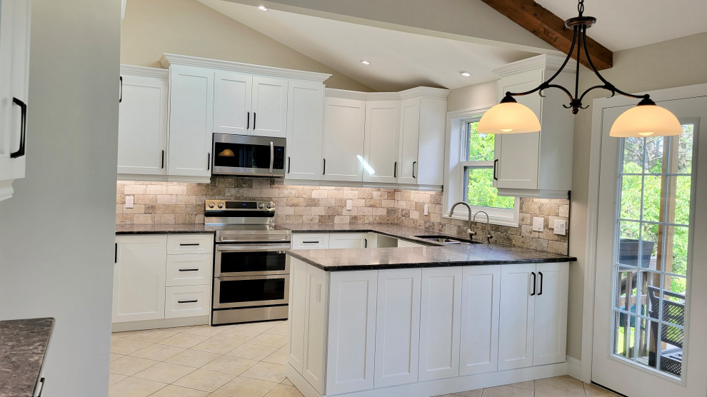 Open concept kitchen - transitional u-shaped open concept kitchen idea with an undermount sink, recessed-panel cabinets, white cabinets, multicolored backsplash, stone tile backsplash, stainless steel appliances and a peninsula