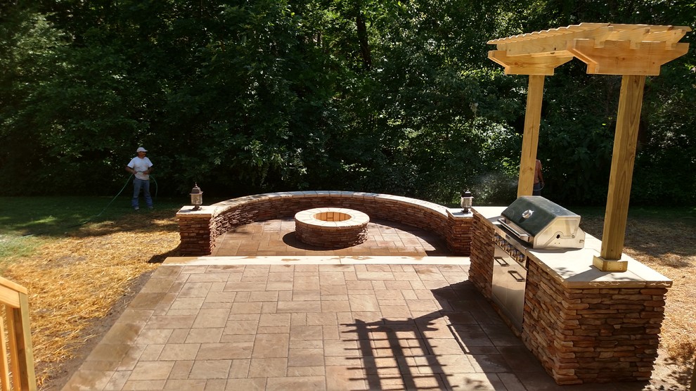 Design ideas for a mid-sized country backyard patio in Raleigh with a fire feature, natural stone pavers and no cover.