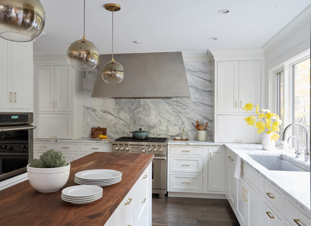 Inspiration for a mid-sized transitional u-shaped eat-in kitchen in Chicago with an undermount sink, shaker cabinets, white cabinets, wood benchtops, white splashback, stone slab splashback, stainless steel appliances, medium hardwood floors, with island, brown floor and brown benchtop.