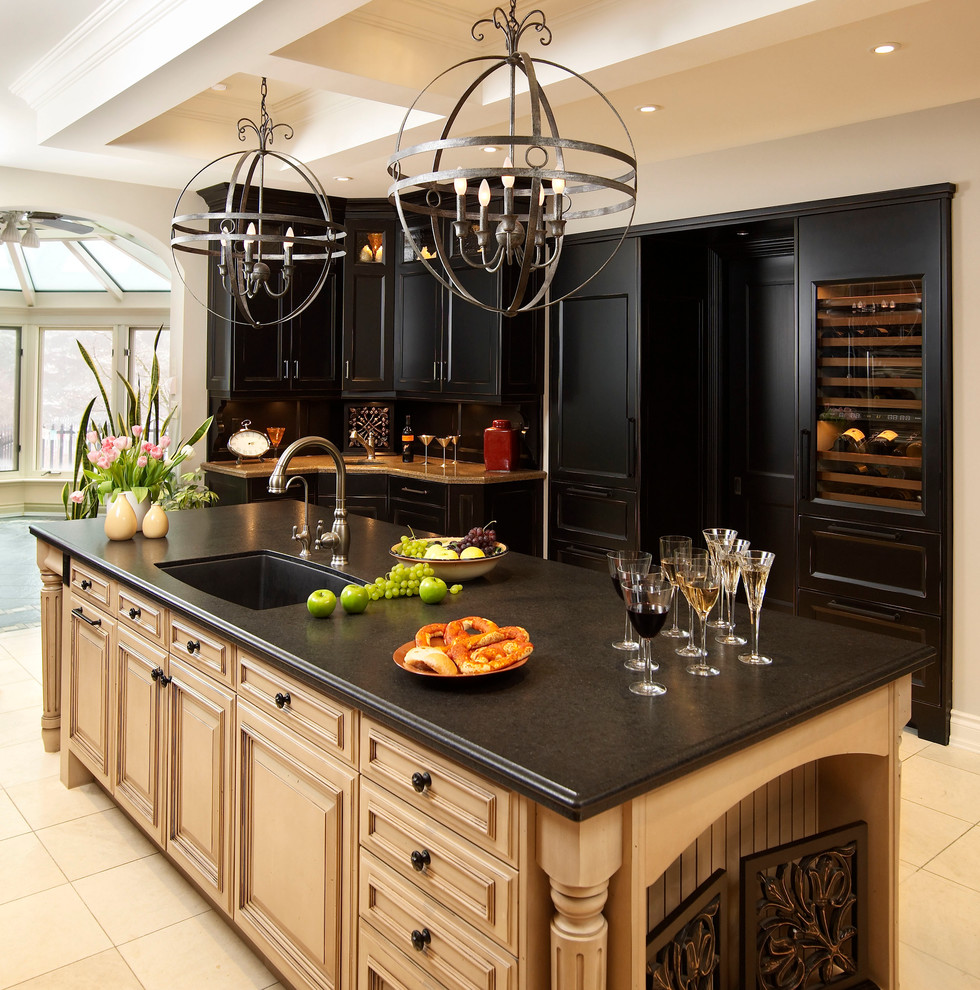 This is an example of a traditional eat-in kitchen in Chicago with an undermount sink, raised-panel cabinets, black cabinets, quartz benchtops and panelled appliances.