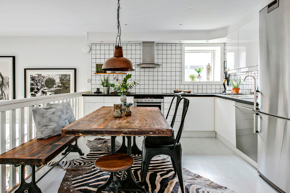 Mid-sized scandinavian l-shaped eat-in kitchen in Gothenburg with flat-panel cabinets, white cabinets, white splashback, stainless steel appliances, painted wood floors, no island and ceramic splashback.