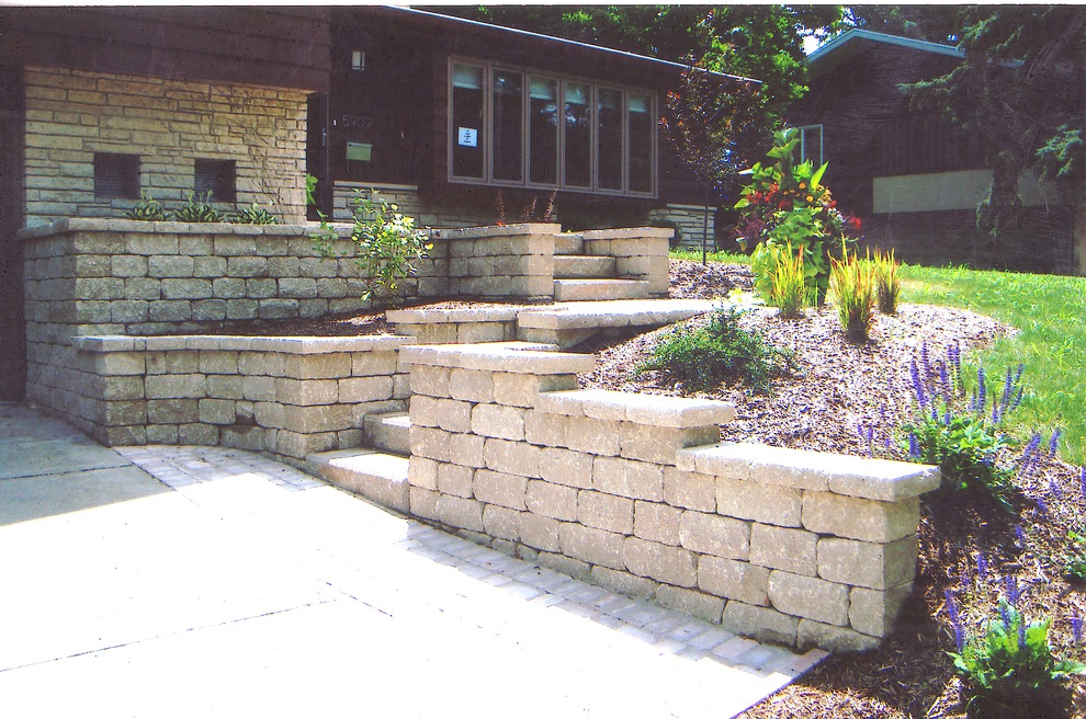Mid-sized traditional front yard garden in Other with a retaining wall and natural stone pavers.