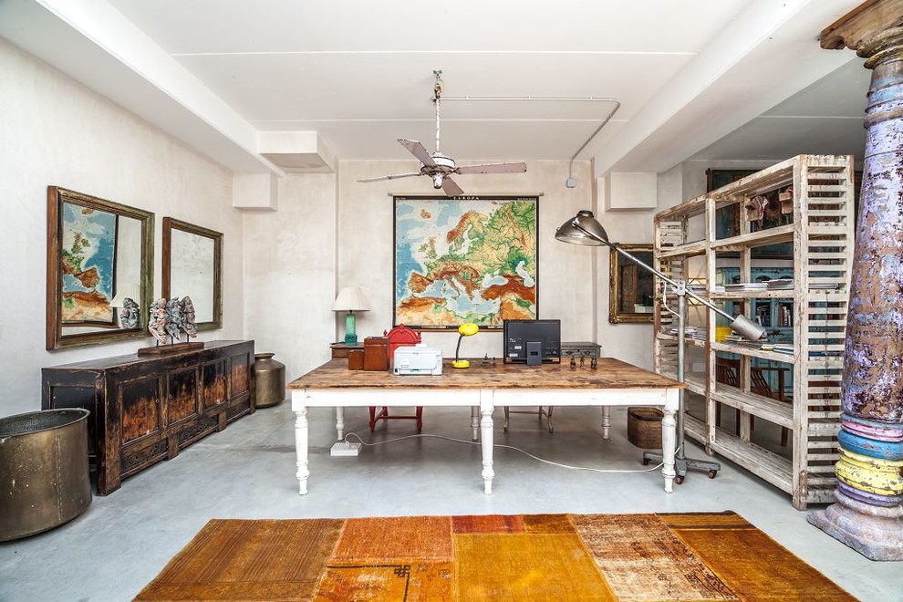 This is an example of an eclectic home office in London with beige walls, concrete floors, a freestanding desk and grey floor.