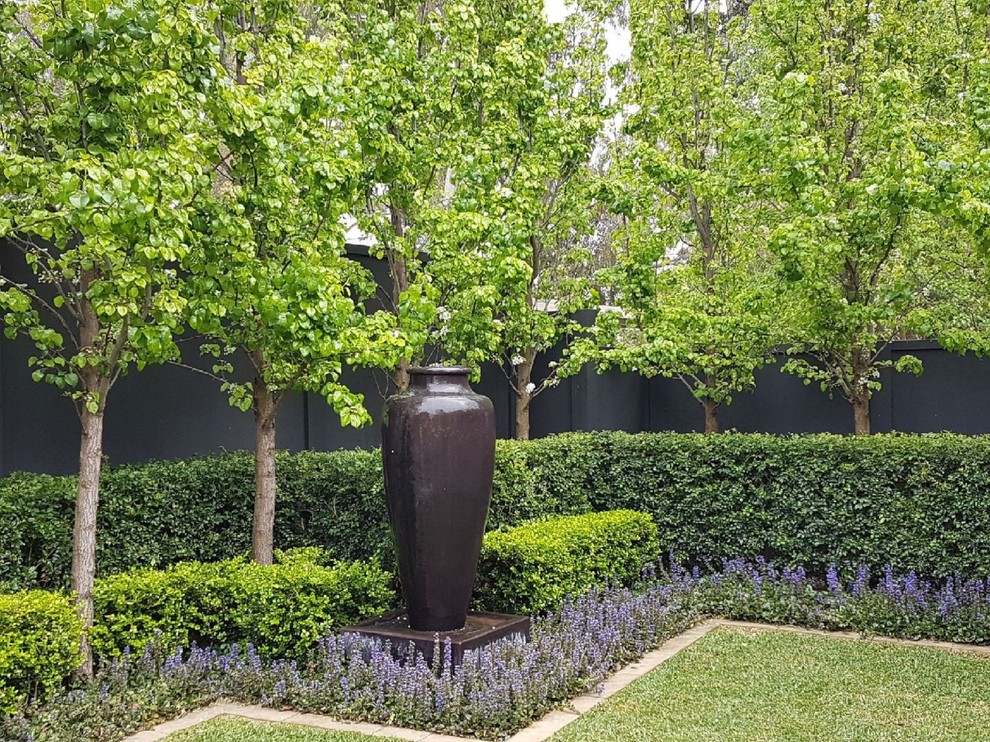Photo of a large traditional front yard full sun formal garden for spring in Adelaide with a water feature and brick pavers.