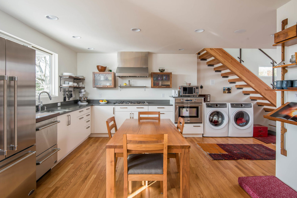 Transitional l-shaped medium tone wood floor eat-in kitchen photo with flat-panel cabinets, white cabinets, quartzite countertops, gray countertops, an undermount sink, stainless steel appliances and no island