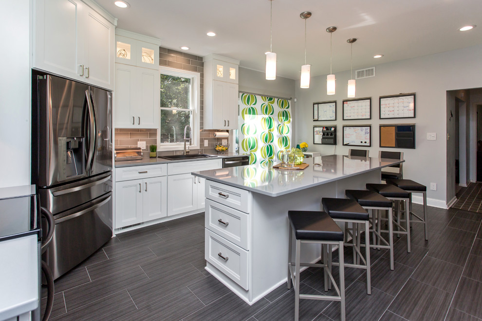 Enclosed kitchen - mid-sized transitional u-shaped porcelain tile enclosed kitchen idea with a drop-in sink, recessed-panel cabinets, white cabinets, quartz countertops, gray backsplash, ceramic backsplash, stainless steel appliances and an island