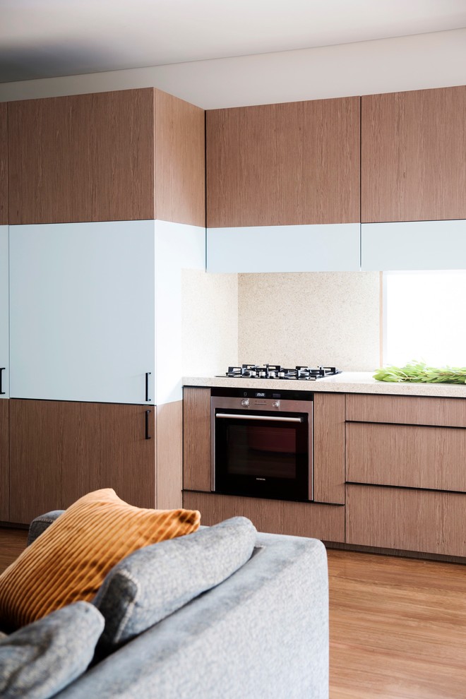 Design ideas for a mid-sized contemporary single-wall open plan kitchen in Sydney with an undermount sink, flat-panel cabinets, medium wood cabinets, quartzite benchtops, white splashback, stone slab splashback, stainless steel appliances, medium hardwood floors and no island.
