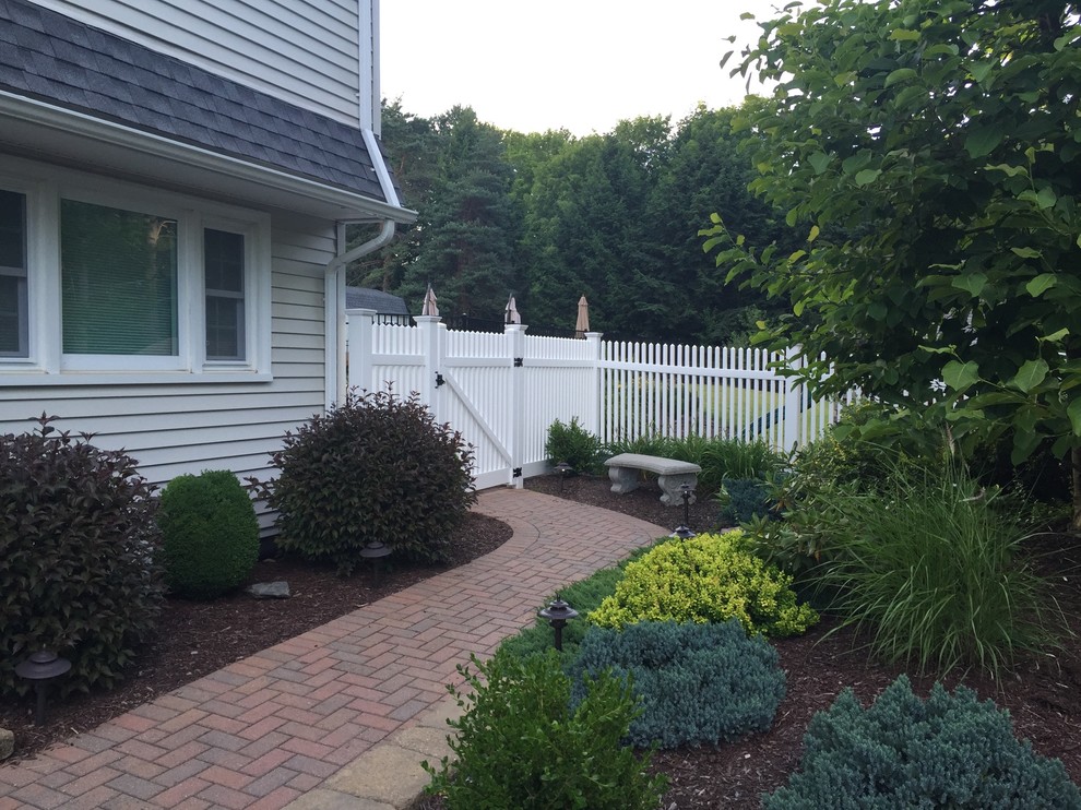 Photo of a mid-sized traditional side yard partial sun garden in New York with a garden path and brick pavers.