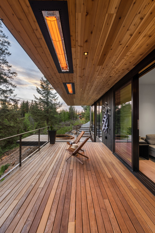 Example of a mid-sized trendy backyard ground level cable railing deck design with a roof extension