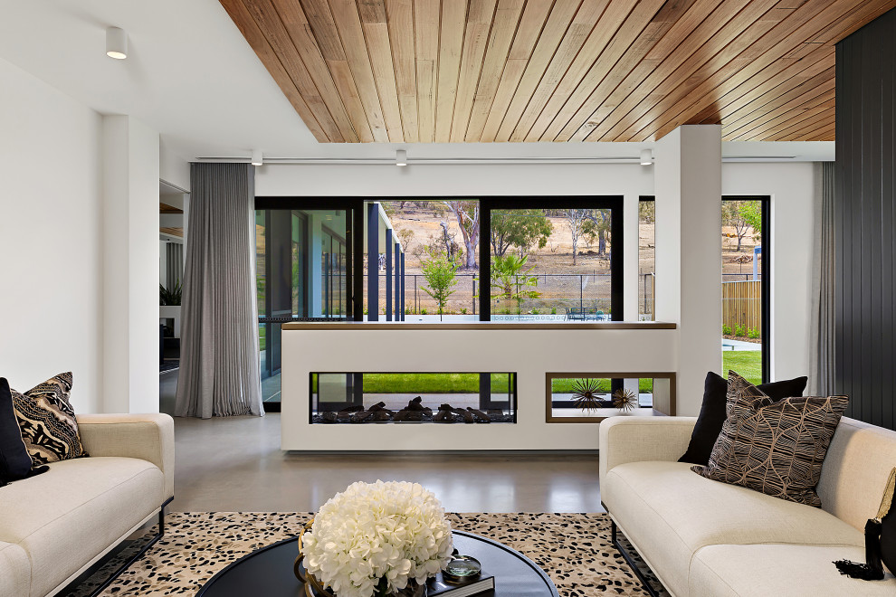 Inspiration for a mid-sized contemporary open concept living room in Canberra - Queanbeyan with white walls, concrete floors, a two-sided fireplace, a concrete fireplace surround, no tv and grey floor.