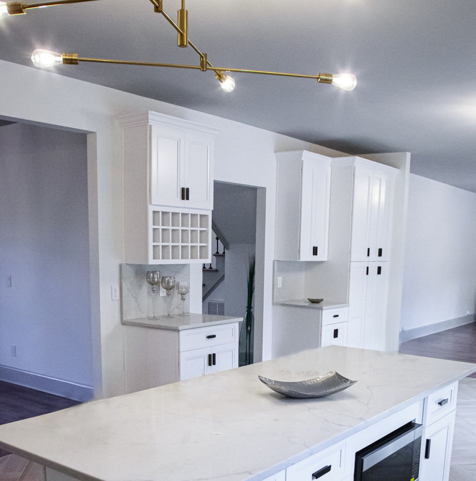 This is an example of a large transitional l-shaped eat-in kitchen in Philadelphia with shaker cabinets, white cabinets, quartz benchtops, white splashback, with island and white benchtop.