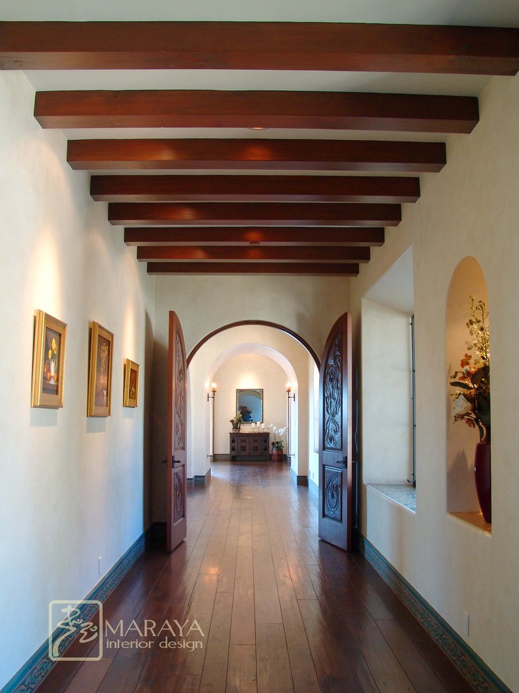This is an example of an expansive country hallway in Santa Barbara with white walls and dark hardwood floors.
