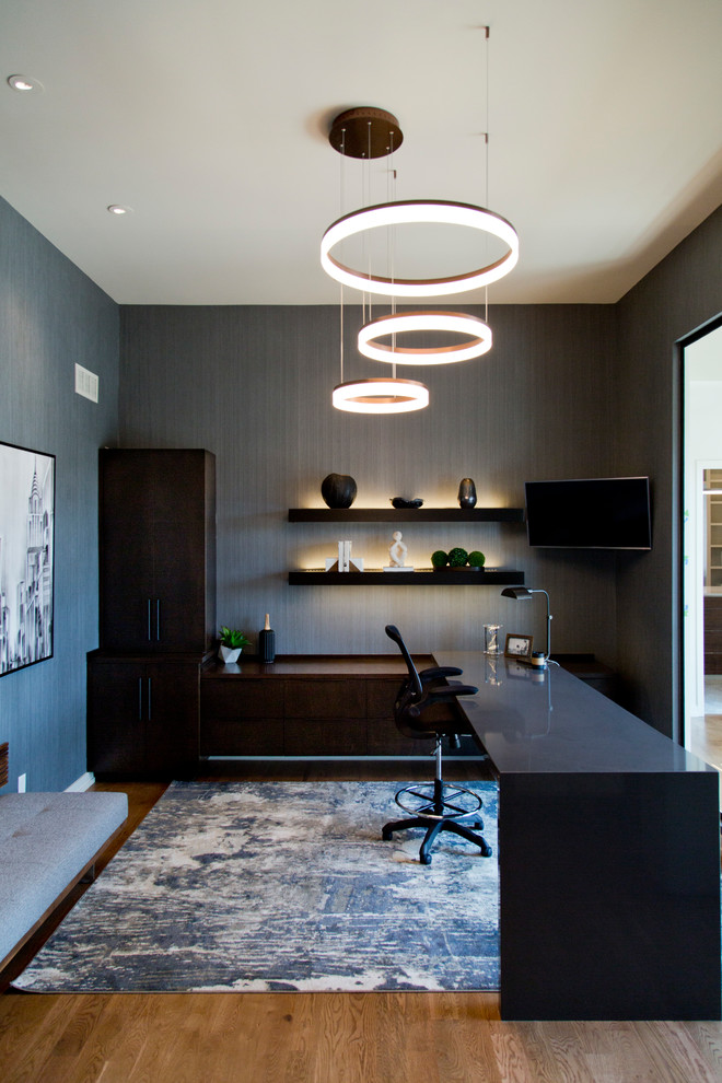 Large contemporary home office in Kansas City with grey walls, medium hardwood floors, a built-in desk and brown floor.