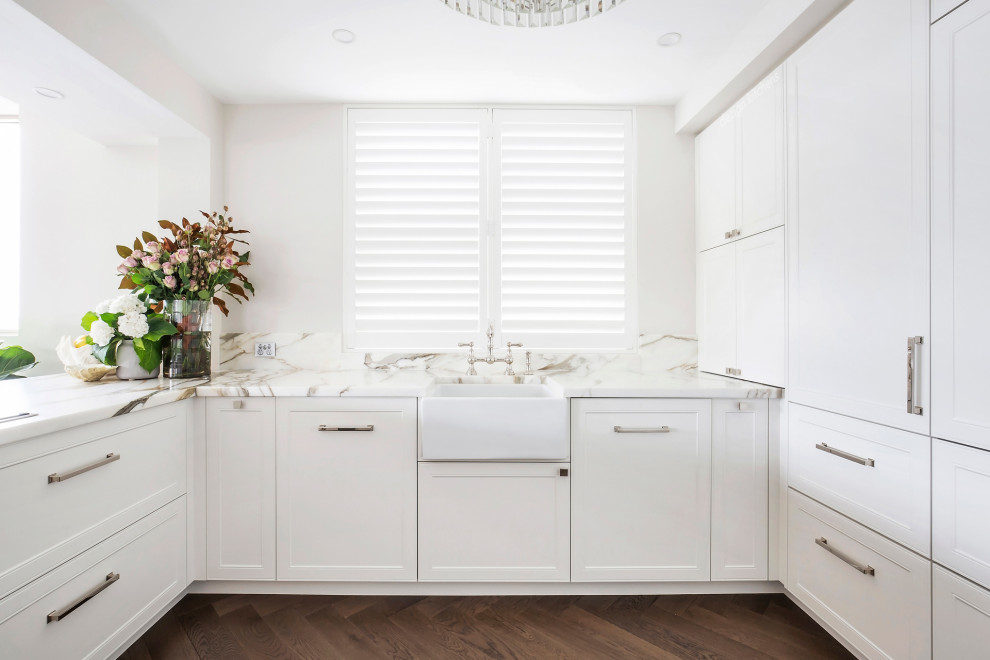Inspiration for a mid-sized transitional u-shaped open plan kitchen in Sydney with a farmhouse sink, recessed-panel cabinets, white cabinets, marble benchtops, multi-coloured splashback, marble splashback, black appliances, medium hardwood floors, with island, brown floor and multi-coloured benchtop.