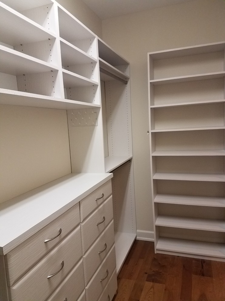 Inspiration for a small traditional gender-neutral walk-in wardrobe in Miami with flat-panel cabinets, white cabinets and medium hardwood floors.
