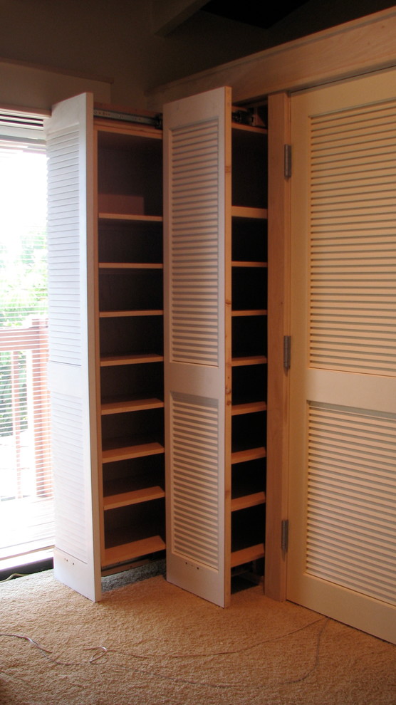 Design ideas for a mid-sized tropical storage and wardrobe in San Diego with carpet.
