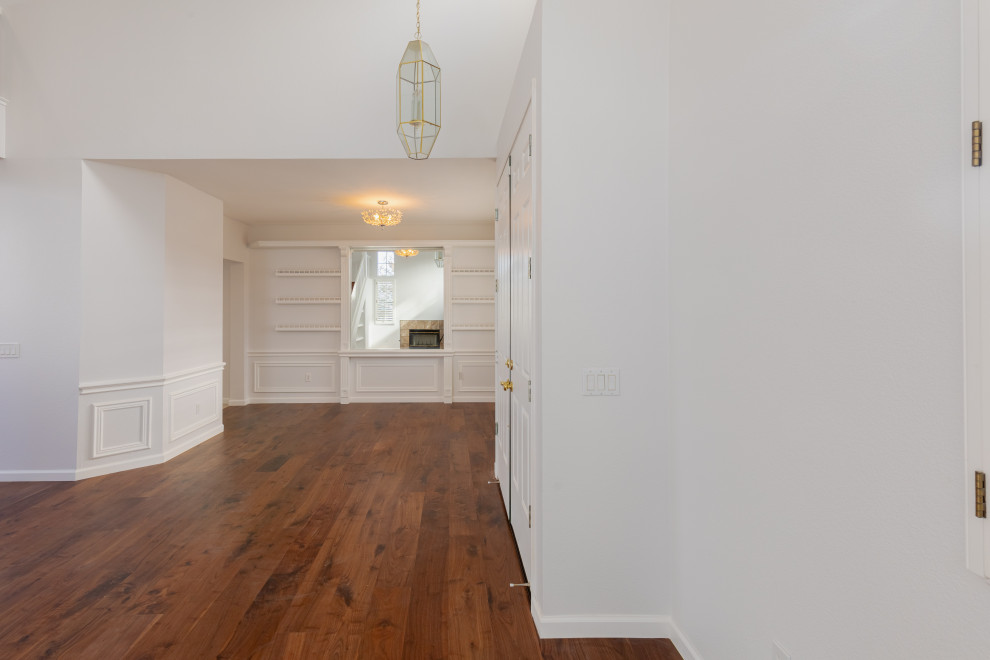 Foto di un corridoio minimalista di medie dimensioni con pavimento marrone, boiserie, pareti bianche, una porta a due ante, una porta bianca e parquet scuro