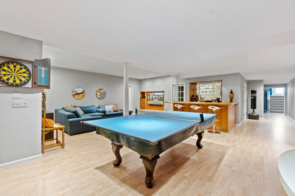 Example of a large beach style light wood floor game room design in Baltimore with gray walls and a wall-mounted tv