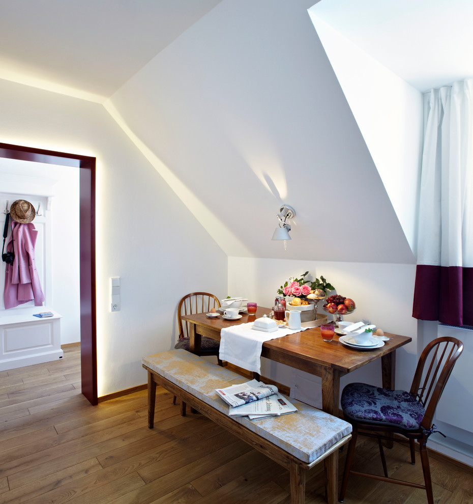 This is an example of a small contemporary dining room in Munich with white walls and medium hardwood floors.